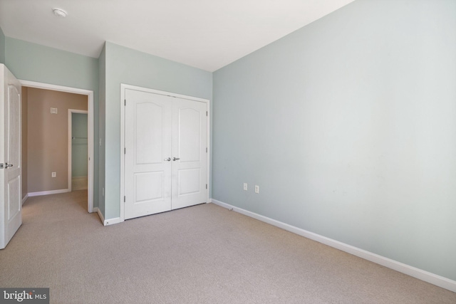 unfurnished bedroom featuring a closet, baseboards, and carpet flooring