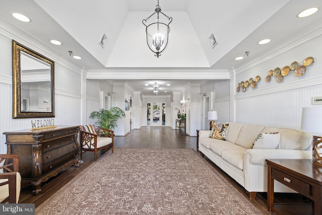 living area with lofted ceiling, visible vents, an inviting chandelier, ornamental molding, and hardwood / wood-style floors