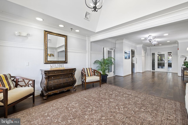 living area with a chandelier, visible vents, crown molding, and wood finished floors