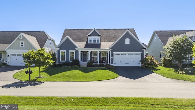 view of front of home with covered porch, driveway, a front lawn, and an attached garage