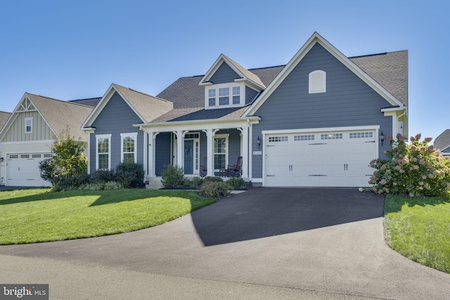 view of front of home with driveway, roof with shingles, a porch, and a front yard