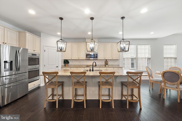 kitchen featuring stainless steel appliances, dark wood-style flooring, cream cabinets, and tasteful backsplash