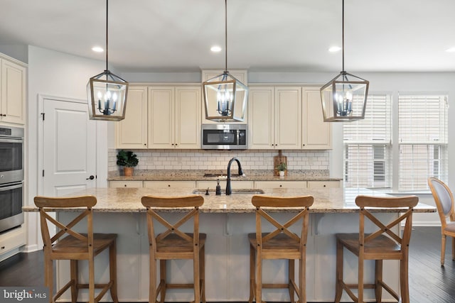 kitchen featuring tasteful backsplash, appliances with stainless steel finishes, light stone counters, and a sink