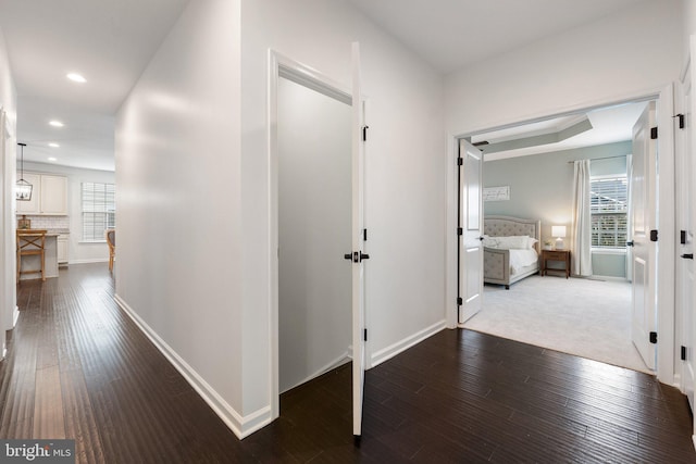 hall featuring baseboards, dark wood-type flooring, and recessed lighting