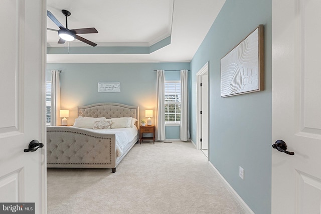 carpeted bedroom featuring a ceiling fan, a tray ceiling, and baseboards