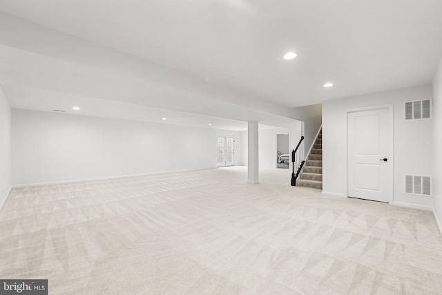 finished below grade area with visible vents, light carpet, stairway, and recessed lighting