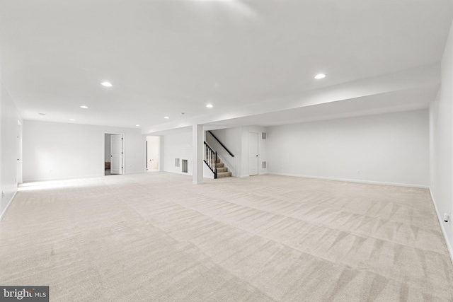 finished below grade area featuring light carpet, baseboards, stairs, and recessed lighting