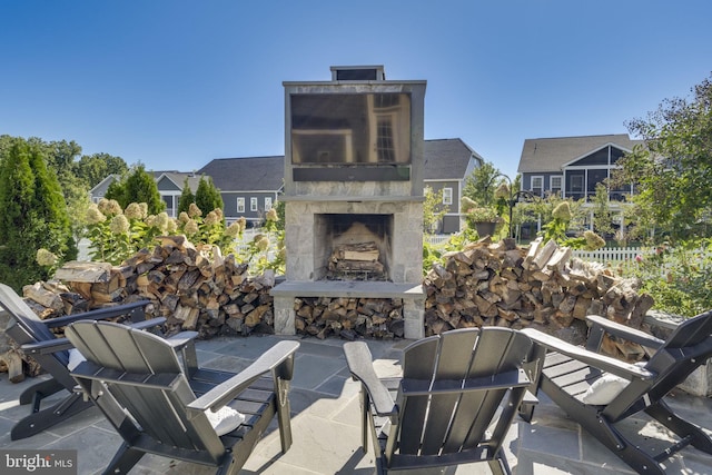 view of patio with an outdoor stone fireplace and fence