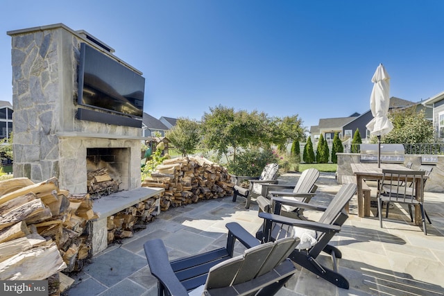 view of patio / terrace featuring an outdoor stone fireplace and grilling area