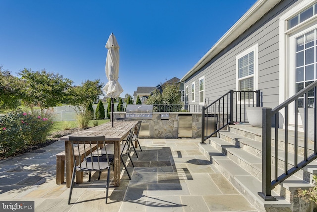 view of patio with outdoor dining space, fence, an outdoor kitchen, and area for grilling