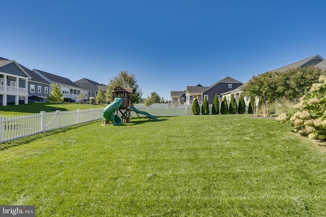 view of yard featuring playground community, a fenced backyard, and a residential view