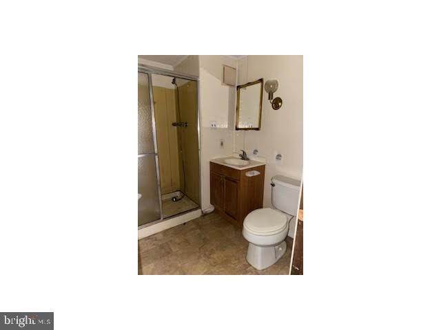 bathroom featuring toilet, a shower stall, and vanity