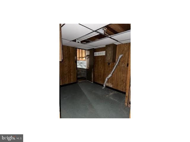 below grade area with a drop ceiling and wood walls