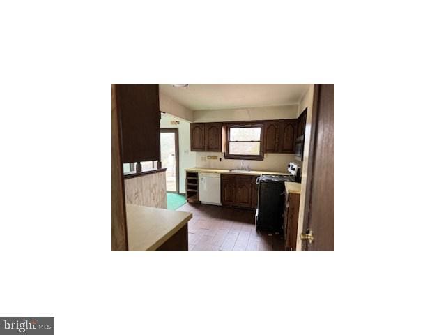 kitchen with light countertops, white dishwasher, black microwave, range, and hardwood / wood-style flooring