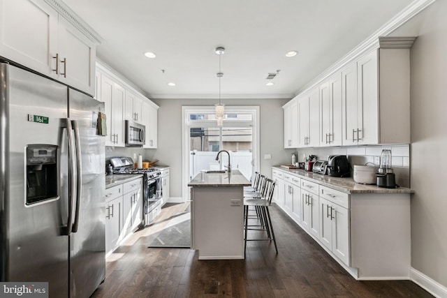 kitchen with stainless steel appliances, a sink, white cabinets, dark wood-style floors, and an island with sink