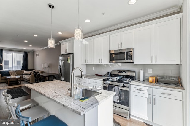 kitchen with appliances with stainless steel finishes, open floor plan, a sink, crown molding, and backsplash