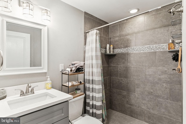 bathroom featuring a tile shower, vanity, and toilet