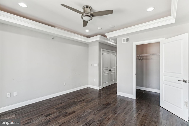 unfurnished bedroom featuring baseboards, visible vents, dark wood-style flooring, a tray ceiling, and crown molding