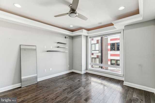 spare room with visible vents, baseboards, dark wood-style floors, a tray ceiling, and crown molding