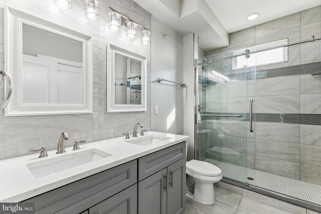 full bath with a stall shower, a sink, and backsplash