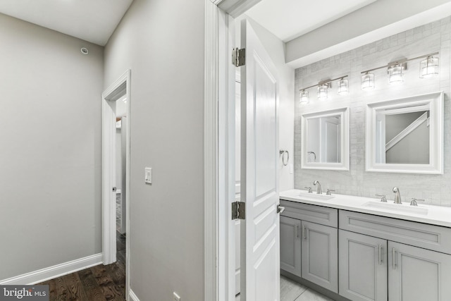 bathroom featuring double vanity, wood finished floors, a sink, and decorative backsplash