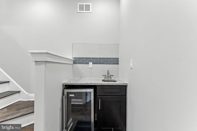 bar featuring wine cooler, visible vents, stairway, a sink, and wet bar