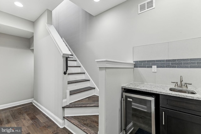 bar featuring beverage cooler, baseboards, visible vents, dark wood-type flooring, and a sink