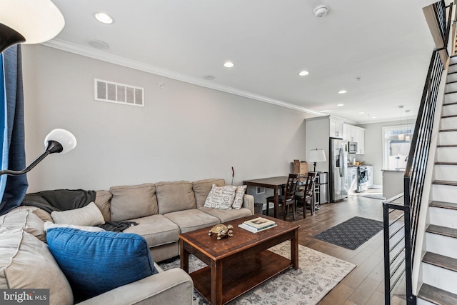 living area with dark wood finished floors, recessed lighting, visible vents, ornamental molding, and stairs