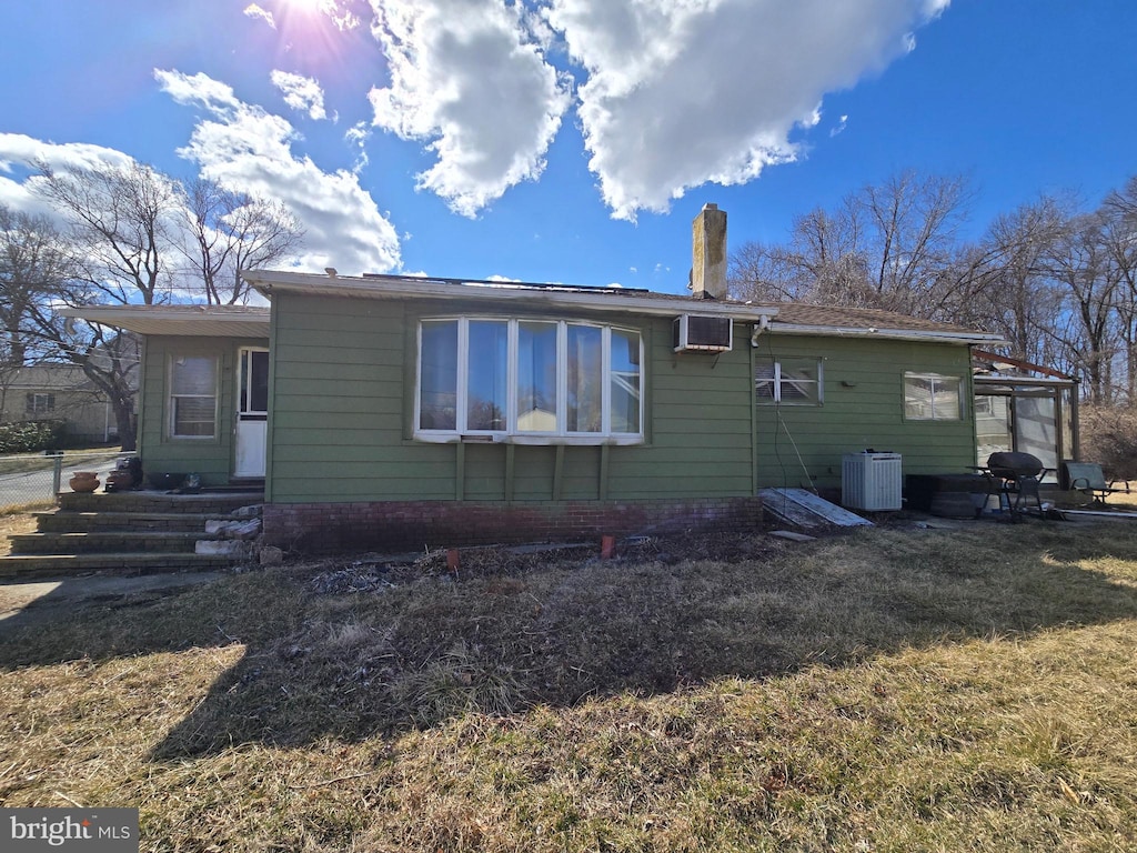 back of house with a yard, central AC unit, and a wall mounted AC