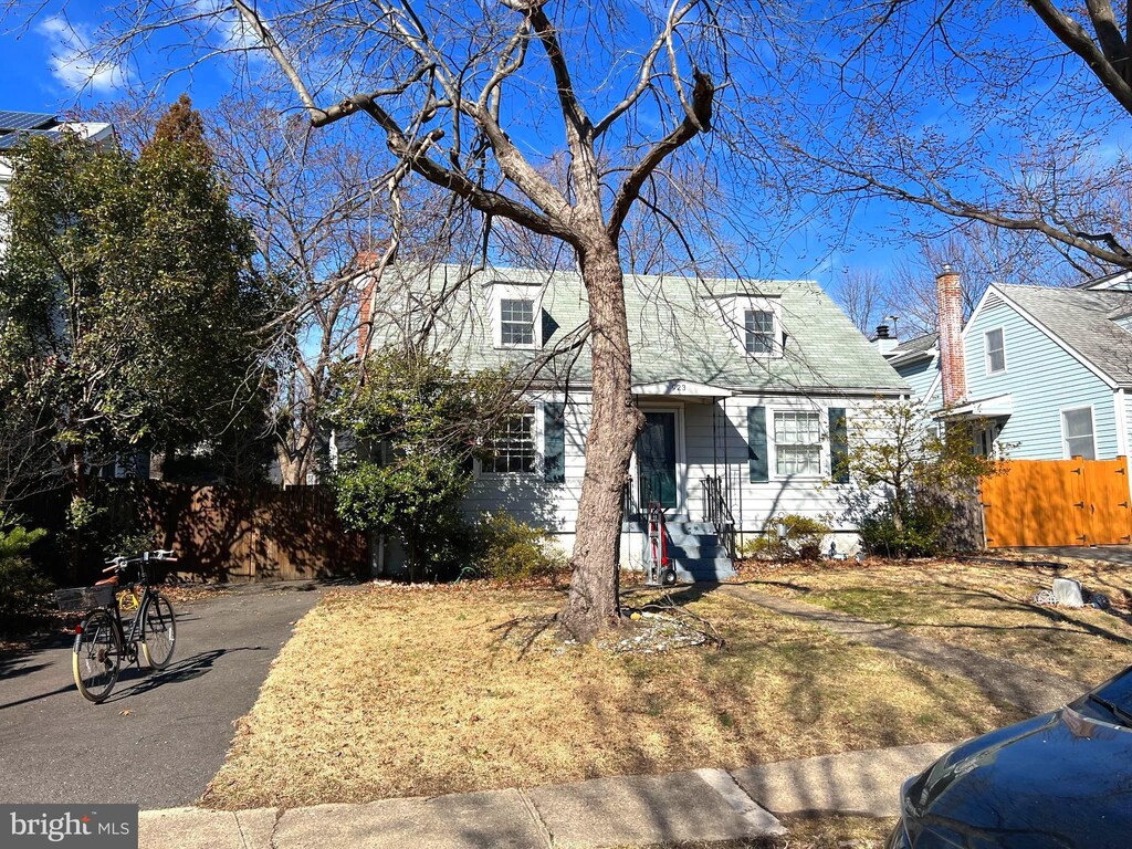 cape cod house featuring aphalt driveway and fence