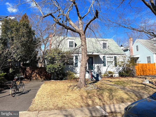 cape cod house featuring aphalt driveway and fence