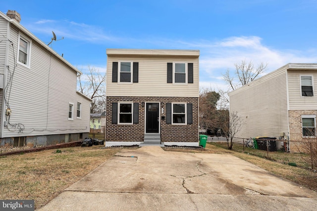 view of front of home featuring entry steps, fence, a front lawn, and brick siding