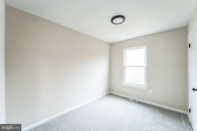 carpeted spare room with visible vents and baseboards