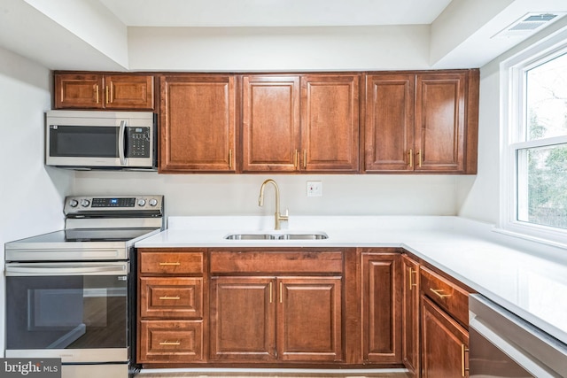 kitchen with stainless steel appliances, light countertops, a sink, and visible vents