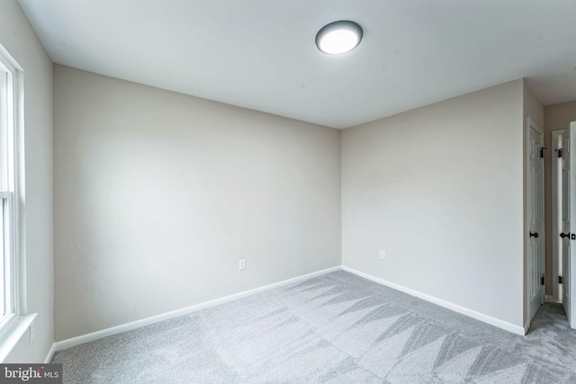 spare room with baseboards and carpet flooring