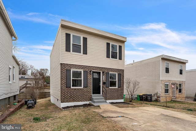 view of front facade featuring entry steps, a front yard, fence, and brick siding