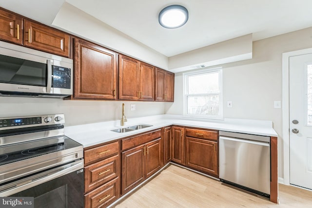 kitchen featuring light wood-type flooring, appliances with stainless steel finishes, light countertops, and a sink