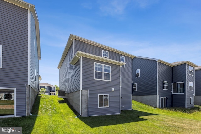 rear view of property with a yard, brick siding, and cooling unit