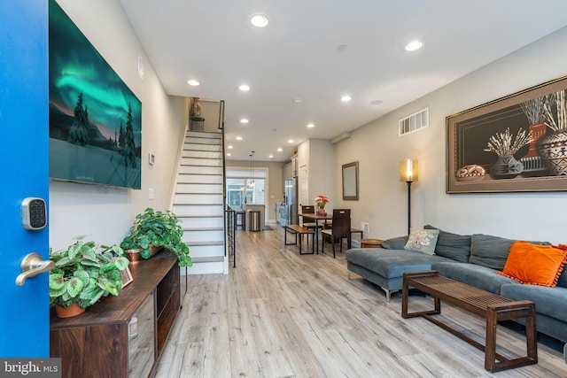 living room featuring stairs, light wood-style flooring, visible vents, and recessed lighting