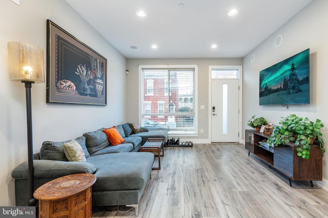 living area with baseboards, light wood finished floors, and recessed lighting