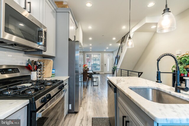 2525 N Hancock St, Philadelphia, PA 19133 - kitchen featuring decorative light fixtures, a sink, stainless steel appliances, light wood-type flooring, and backsplash