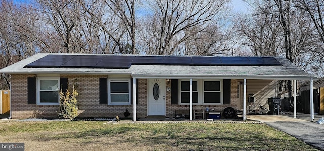 view of front of property featuring brick siding, solar panels, a porch, a front yard, and fence