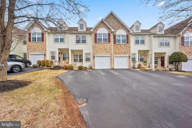 view of property with driveway, stone siding, and a garage