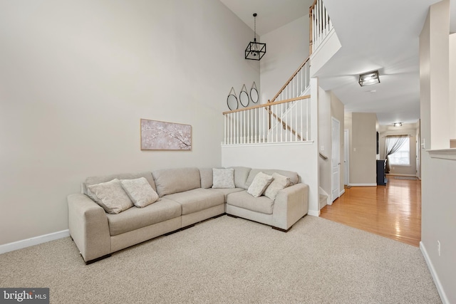 living room featuring wood finished floors, stairway, carpet flooring, and baseboards