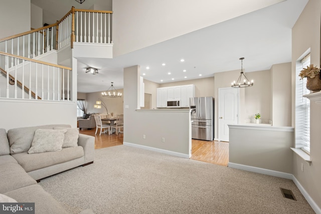 living room featuring light carpet, baseboards, visible vents, and an inviting chandelier