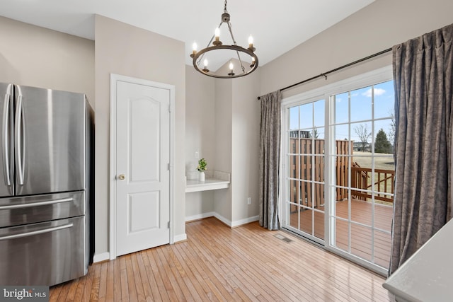 dining space with light wood finished floors, visible vents, baseboards, and a chandelier