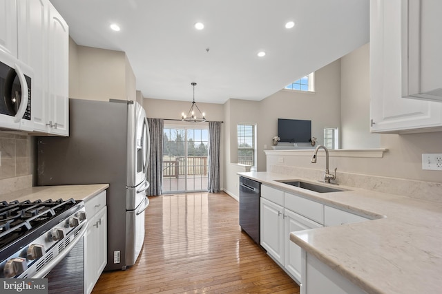 kitchen with light wood finished floors, appliances with stainless steel finishes, a sink, and white cabinets