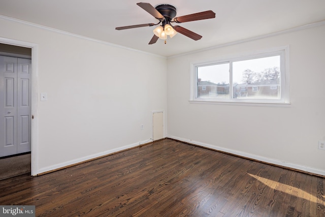 empty room featuring ornamental molding, dark wood finished floors, baseboards, and a ceiling fan