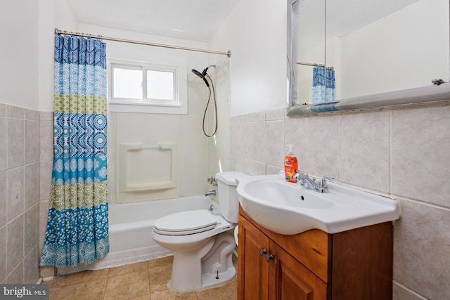 full bathroom with toilet, shower / tub combo with curtain, tile patterned floors, vanity, and tile walls