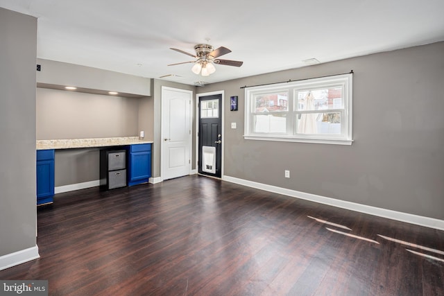 interior space with blue cabinetry, baseboards, dark wood-type flooring, and built in study area